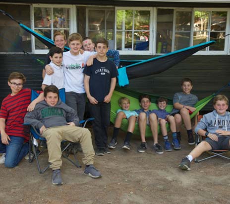 A group of boys of varying ages hanging out in hammocks at their boys sleep away camp in Pennsylvania
