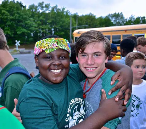 Two campers of different ethnicities and backgrounds embracing each other and smiling for the camera at their Summer Camp in PA