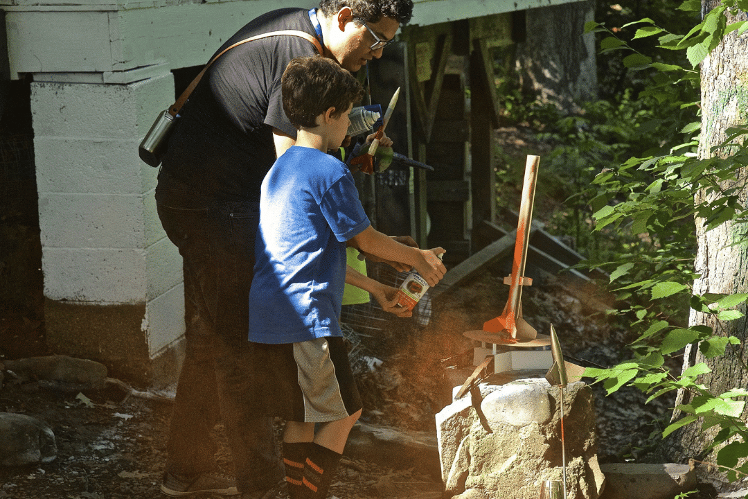 adult guiding camper during hands-on activity