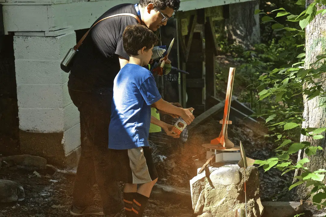 adult guiding camper during hands-on activity