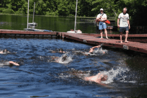Campers swimming in a lake race at summer camp waterfront activities