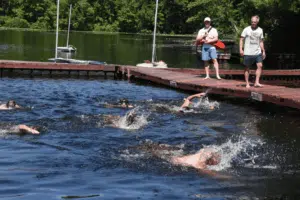 Campers swimming in a lake race at summer camp waterfront activities