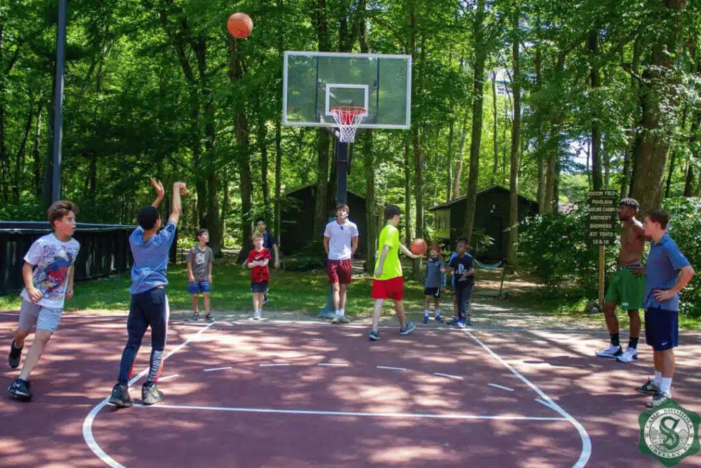 Basketball game at Camp Shohola for Boys showing sports programs offered at a boys summer camp in a wooded outdoor setting